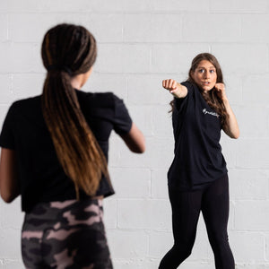 Woman in GJWB black boyfriend tee throwing a punch