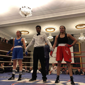 2 boxers in the ring with official waiting for judges results