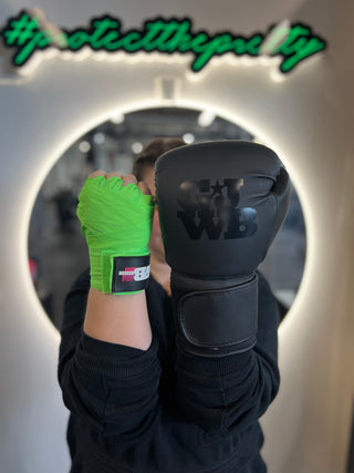 a girls holding hands up with one hand having a neon green handwrap and the other with a boxing glove on 