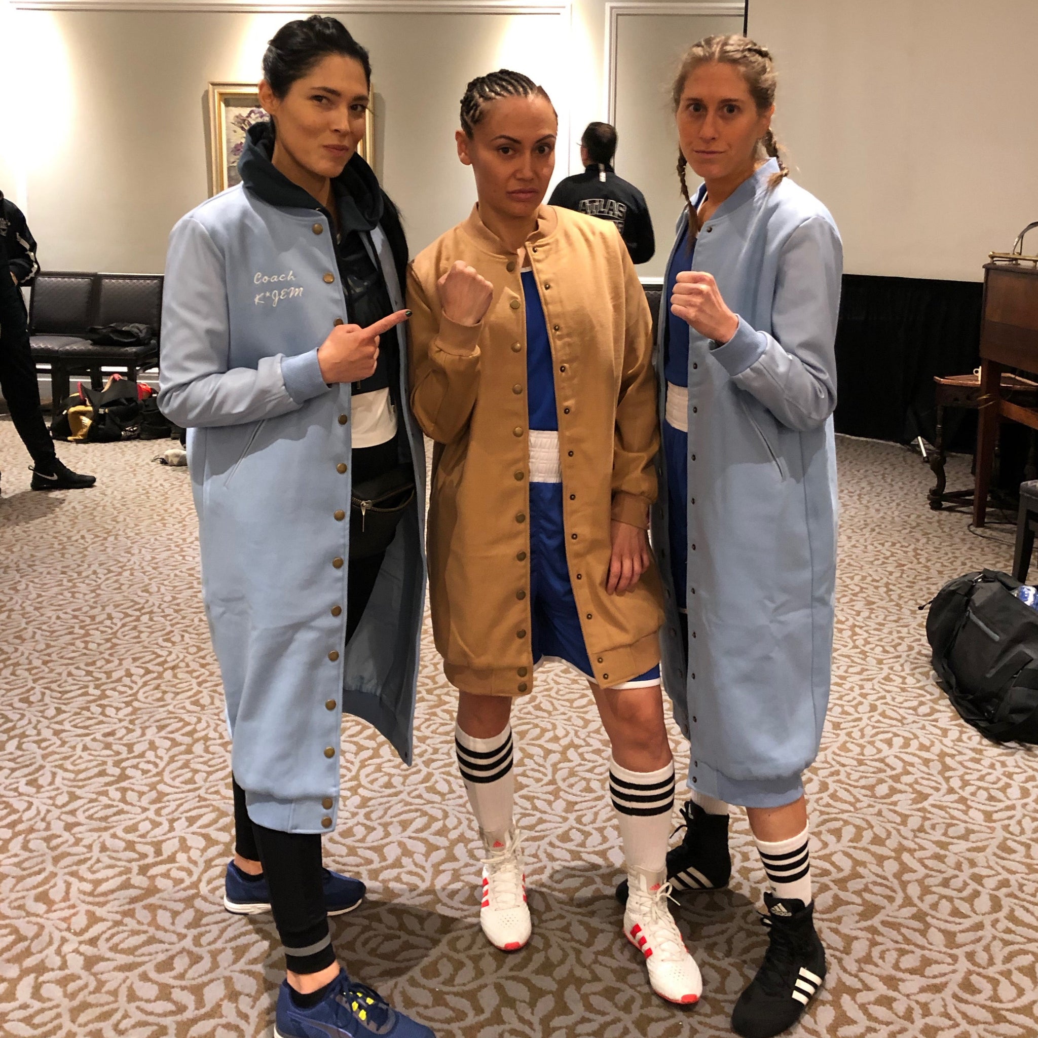 3 girls with 2 powder blue and 1 camel coloured long vegan leather jacket with their fists up