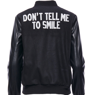 don't tell me to smile saying written on the back of a vegan leather varsity jacket 